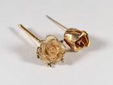 paire de boucles d'oreilles en forme de fleur, de couleur dorée, ornées de cristaux verts sur un fond blanc