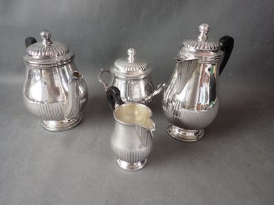 three pieces of silver tea and coffee set sitting on a table