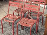 quatre chaises rouges en métal posées sur un tapis dans un salon