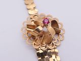 a close up of a gold bracelet with a pink stone