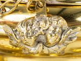a close up of a gold vase with a flower on it