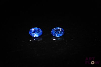 a pair of blue glass beads sitting on top of a black surface