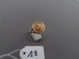 une bague sur laquelle est posé un penny et à laquelle est attachée une étiquette de prix