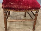 an old wooden chair with a red velvet seat on a wooden floor