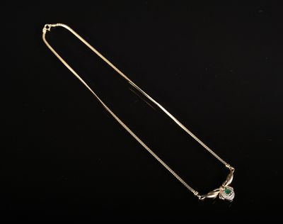 un collier en or orné d'une pierre verte sur fond noir