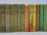 several old books are lined up in a row on a white surface