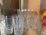bottles and glasses on a glass shelf in front of a window