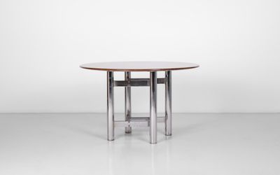 une table à manger ronde avec des pieds chromés et un plateau en bois