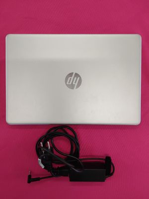 Ordinateur portable HP avec son cordon d'alimentation et son chargeur, posé sur une surface rose