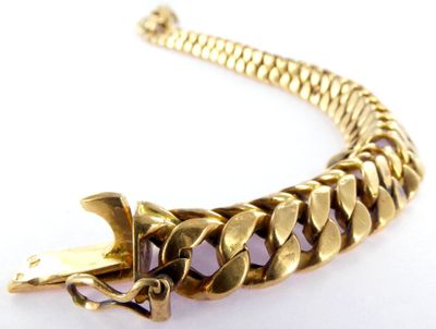 a close up of a gold chain bracelet on a white surface