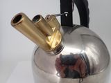 a silver tea kettle with a gold handle on a white table
