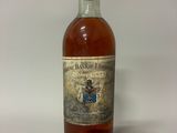 une vieille bouteille de whisky posée sur une table blanche