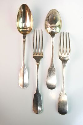 five silver spoons and two silver forks on a white surface