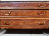 a wooden chest of drawers with marble top and brass handles