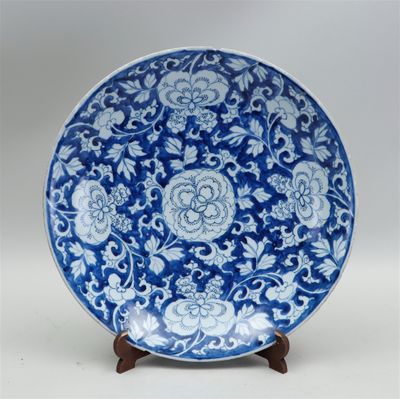 assiette bleue et blanche ornée de fleurs et de rinceaux, posée sur un socle en bois