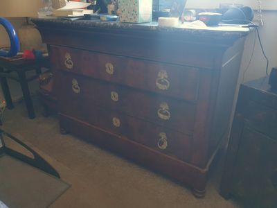 une commode placée dans un coin de la pièce, sur laquelle est posé un miroir