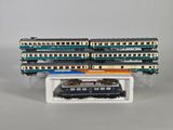 Plusieurs trains miniatures sont empilés les uns sur les autres sur une surface blanche