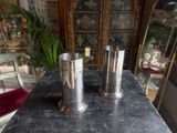 two silver vases sitting on a table in a room