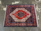 a red and black rug on a concrete floor