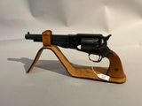 le pistolet est posé sur un socle en bois, sur une surface blanche