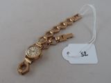 a gold wrist watch with a white dial on it
