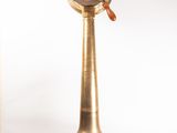 a brass clock on a wooden stand with a white background