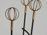 three black and gold metal sculptures in a vase on a white surface