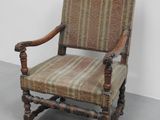 une vieille chaise dont l'assise rembourrée est usée et qui a des pieds en bois