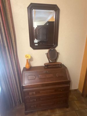 une commode sur laquelle sont posés un miroir et un vase