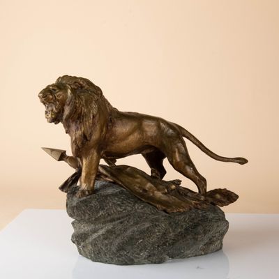 bronze statue of a lion on a rock on a white surface