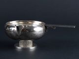 a silver bowl with a spoon in it on a black surface
