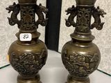une paire de vases anciens en laiton posés sur une table devant un mur