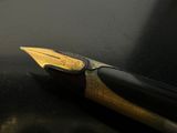 a black pen with a gold tip on a black surface