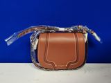 un petit sac à main marron muni d'une poignée en plastique transparent, posé sur une table
