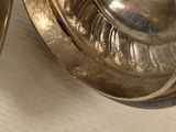 two silver dishes sitting on a table next to each other