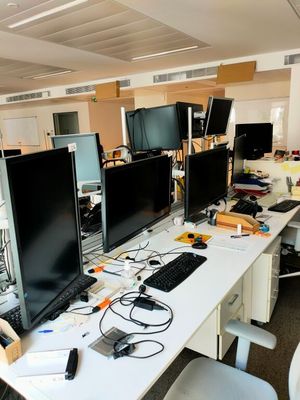 trois écrans d'ordinateur posés sur un bureau dans un bureau