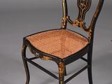 paire de chaises peintes en noir et or, avec des assises en osier