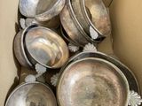 a cardboard box with a bunch of silver dishes inside of it