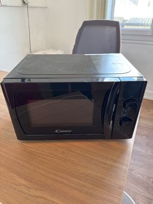 a black microwave sitting on a wooden table in a room