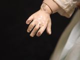 a close up of a doll ' s hands with a white dress on