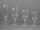 four wine glasses and a vase on a table with a gray background