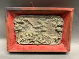 une image représentant une boîte rouge ornée d'un relief représentant un homme et une femme dans un jardin