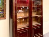 a large wooden cabinet with glass doors and a clock on the wall