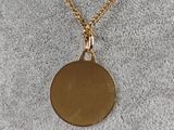 a gold necklace with a small disc on a gold chain