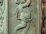 a statue of a cupid on the side of a building