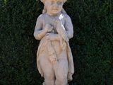 a statue of a boy holding a bird in a garden