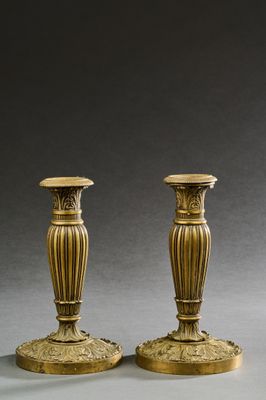 une paire de bougeoirs anciens en laiton sur socles, sur fond gris