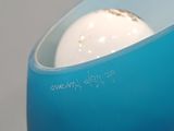 a blue vase sitting on a table with a white ball in it