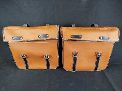 deux sacs de voyage en cuir marron posés sur une surface noire