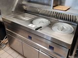 un plan de travail en acier inoxydable sur lequel sont posés trois récipients, dans une cuisine professionnelle